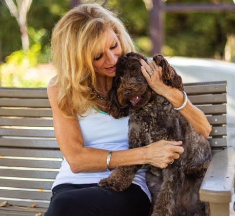 Paige on a garden bench hugging a curly chocolate-brown dog