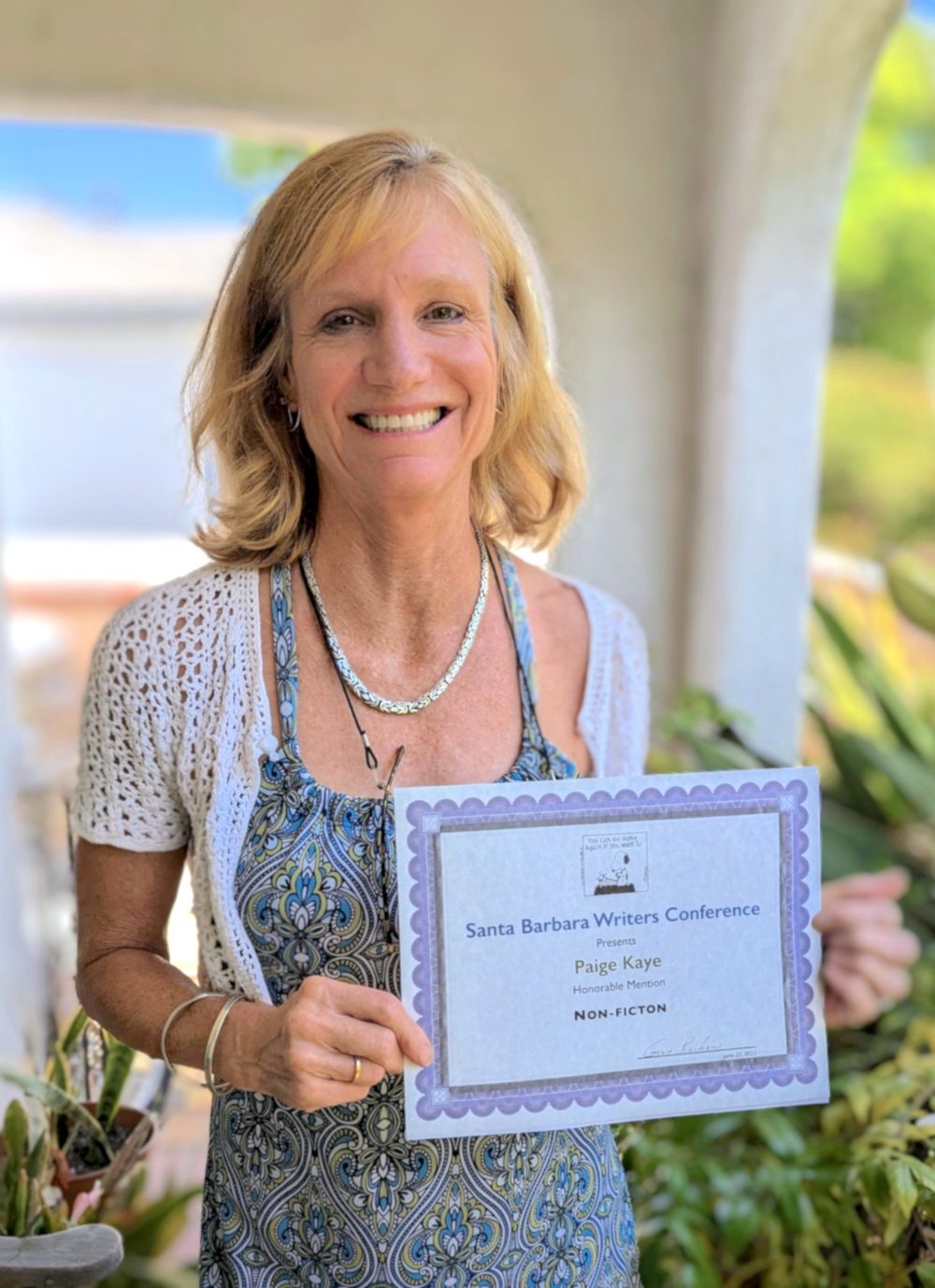 Paige holding a Santa Barbara Writers Conference certificate for Honorable Mention in Non-fiction